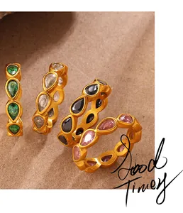 Gros plan de bagues dorées 18 carats avec zircons colorés en forme de poire sur papier