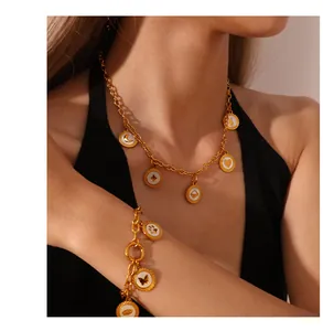 Close-up of a gold necklace and bracelet set featuring moon and heart charms on a model