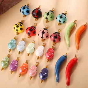 Colorful ceramic ladybug and heart charms with golden rings on beige background