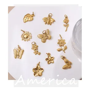 Detailed view of gold stainless steel insect and floral charms on a white tray