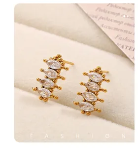 Détail de boucles d'oreilles dorées avec quatre zircons marquise sur velours