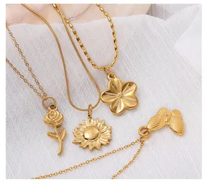 Detail of four gold stainless steel pendants with rose, sunflower, flower, and butterfly