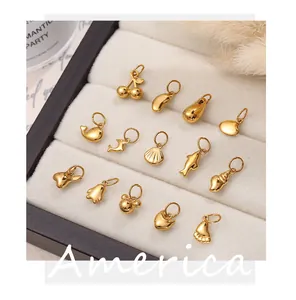 Close-up of assorted gold-plated DIY charms including heart and dolphin shapes on jewelry tray
