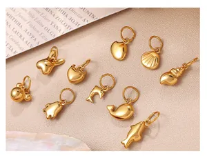 Macro shot of assorted golden stainless steel charms like hearts and animals on pink background