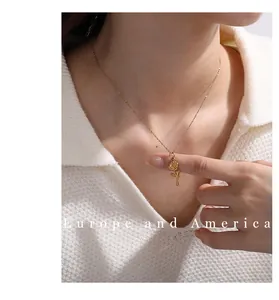 Close-up of a delicate gold rose pendant necklace worn by a model on a white knit sweater