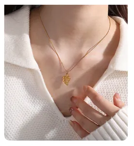 Golden leaf pendant necklace on fine snake chain shown over white knit sweater