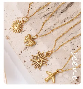 Detail view of gold-plated necklaces with sun, bow, evil eye, and plane pendants