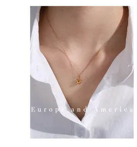 Close-up of a minimalist gold pendant necklace featuring a polished mouse silhouette