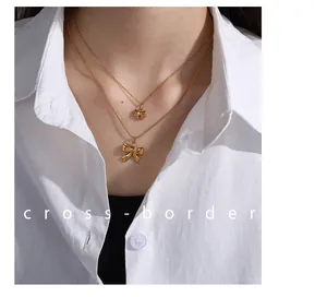 Detail of double-layered gold bow pendant necklace set worn over a white shirt