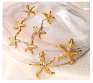 Detalle de pendientes colgantes y de botón con forma de estrella de mar bañados en oro