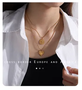 Detailed view of layered gold necklace with compass and heart charms on model