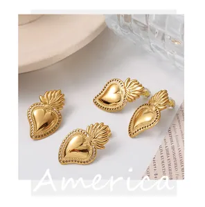Detailed close-up of gold-plated sacred heart earrings on a minimalist white surface