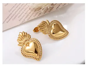 Close-up of gold Sacred Heart earrings with ray texture and beaded edges on white decor