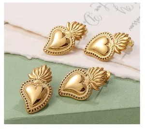 Macro detail of Sacred Heart gold-plated stud earrings with polished flame and heart motifs