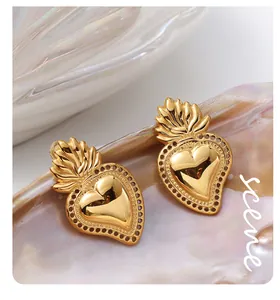 Macro detail of vintage gold heart earrings with flame-shaped crown on iridescent shell