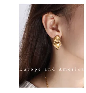 Close-up of vintage golden sacred heart stud earrings with flame details on a female model