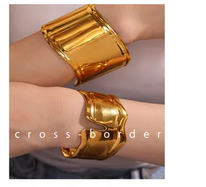 Dettaglio di bracciali aperti placcati oro 18 carati lisci e ondulati sul polso