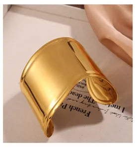 Dettaglio di un ampio bracciale a fascia aperta in acciaio inossidabile placcato oro 18k lucido