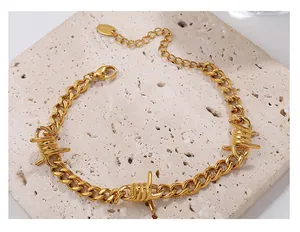 Detail eines goldenen Dornen-Gliederarmbands mit s925-Anhänger auf beigem Stein