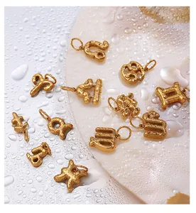 Detailed macro view of 18k gold zodiac pendants with hammered metal texture on wet surface