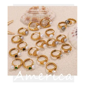 Detail of assorted 18k gold plated hoop earrings with pearls and gemstones on beach sand