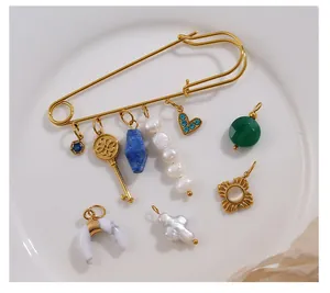 Vista macro de broche de imperdible dorado con dijes de perlas y piedras azules