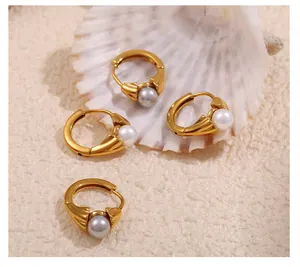 Close-up of gold 18k plated stainless steel pearl hoop earrings on a shell