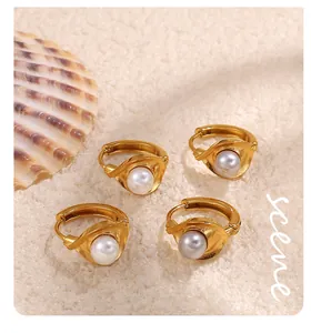 Macro view of gold-plated hoop earrings with pearls on sand and seashell backdrop