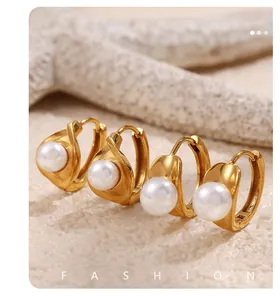 Detailed view of pearl earrings in 18k gold finish set against a beach starfish background