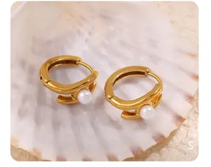 Macro detail of 18k gold earrings with smooth pearls on a textured shell surface