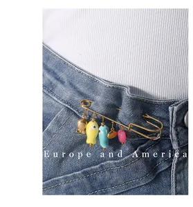 Primer plano detallado de un broche de imperdible dorado con dijes coloridos en denim