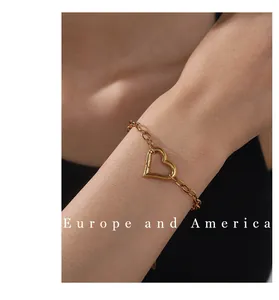 Macro detail of a 18k gold plated hollow heart charm bracelet on a model wrist