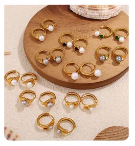 Detail of 18k gold hoop earrings with pearls and colorful gemstones on a wooden tray