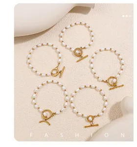 Primer plano de pulseras de perlas con cierre de palanca dorado en fondo minimalista