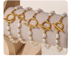Detalle macro de pulseras de perlas asimétricas con varios cierres de palanca dorados