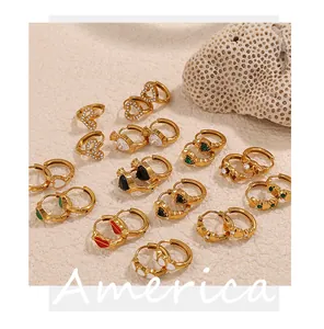 Collection de boucles d'oreilles dorées en zircon et cœurs émaillés sur fond de sable