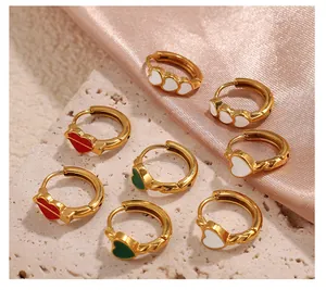 Détail de boucles d'oreilles dorées avec cœurs en émail et lèvres rouges sur soie