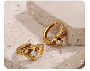 Gros plan de boucles d'oreilles cœur dorées avec zircon incrusté sur pierre blanche