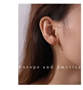 Vue détaillée de boucles d'oreilles cœur dorées avec cristal sur l'oreille d'un mannequin