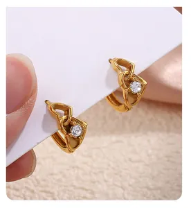 Détail macro de boucles d'oreilles cœur dorées avec zircon brillant sur fond textile doux
