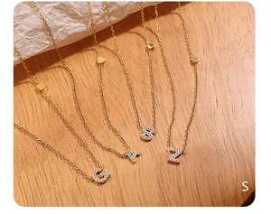 Detail of 18K gold plated initial necklaces with zircon inlay and small heart charm