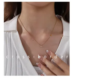 Detail of 18K gold plated letter W pendant necklace with paved crystals on a model