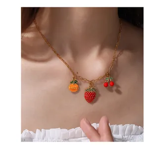 Detail of colorful fruit pendants including lucky orange, strawberry, and cherries on gold chain