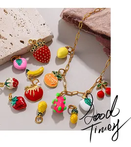 Detail of gold-plated bracelet with colorful enamel fruit charms on stone background