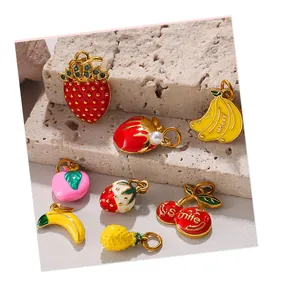 Macro shot of fruit-shaped enamel charms like strawberry and banana with gold plating