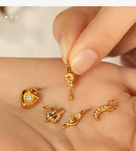 Miniature 18K gold plated charms with zircon inlay shown on palm for size scale