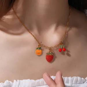 Gold-plated necklace featuring strawberry, cherry, and Lucky fruit pendants on a model