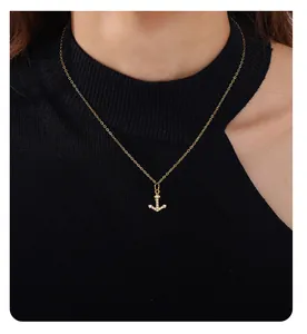 Detailed view of a gold anchor pendant with white crystals on a delicate chain