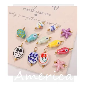Macro detail of handmade ceramic charms with 18K gold plated rings and painted floral motifs