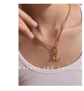 Detail of 18K gold-plated star and moon charms with zircon stones on a gold necklace